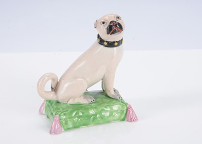 Lot 393 - An English pearlware pug dog seated on a cushion, circa 1820