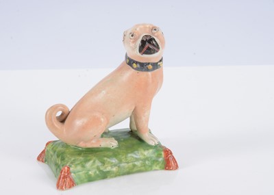 Lot 394 - An English pearlware pug dog seated on a cushion, circa 1820